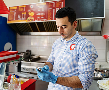 a middle eastern male takeout restaurant owner ordering on smartphone